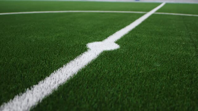 White markings on indoor football field lawn closeup. Soft thick artificial grass minimizes impact of falls and reduces injury risk
