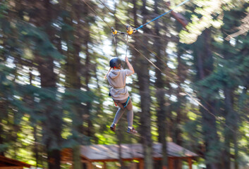 A girl bungee-sliding in the trees in summer