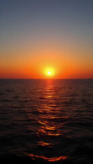 Obraz premium A peaceful sunset over the sea with warm golden hues reflecting on the water, creating a tranquil atmosphere perfect for relaxation and beachside retreats.