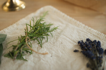 Fresh spring of rosemary and lavender on linseed tablecloth. Wooden table. Work with herbs
