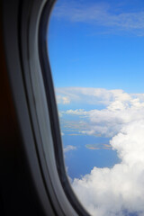 view of clouds from high above an airplane window during a transoceanic flight