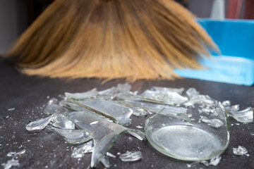 Broken glass was scattered on floor of home,cracked to small shattered and sharp,shards of glass and broom with dustpan,be careful when cleaning up,accident,careless,housework,housekeeping concept