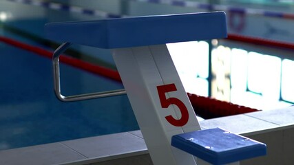 Numbered starting block located on edge of swimming pool with clear water separated by dividing lines. Spacious pool equipped for sports and rehabilitation purposes