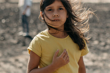 Portrait of thoughtful girl looking at camera close up, indian spanish child in yellow t-shirt,...