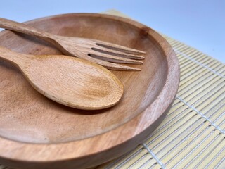 A wooden plate with a spoon and fork, ideal for serving food.