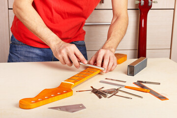 Guitar technician crowning frets on guitar neck with special fret files.