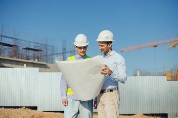 Team of building experts with drawings inspecting new development site