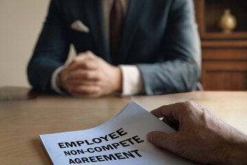 employee handing over a non-compete agreement to an executive in a corporate setting. The document...