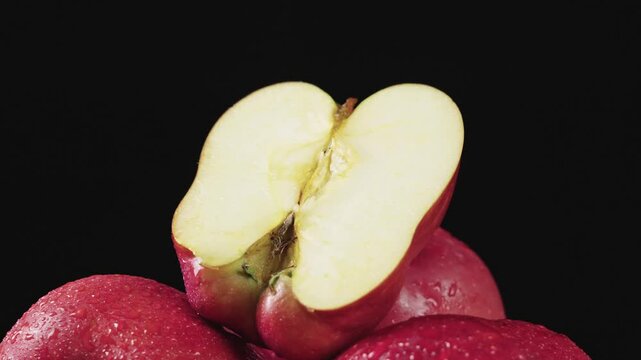 Fresh red delicious apple cut in half on black background.