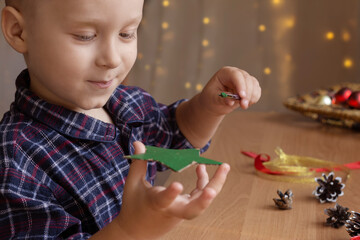 boy making christmas decor. child draws with paints
