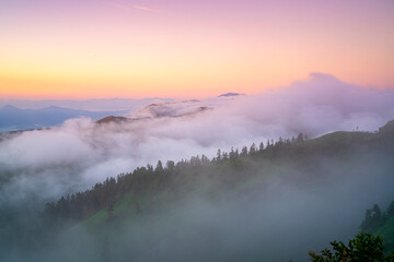 This attached photo shows the view from a mountain peak reached by car early in the morning, with the mountains illuminated by the morning sun (alpenglow).