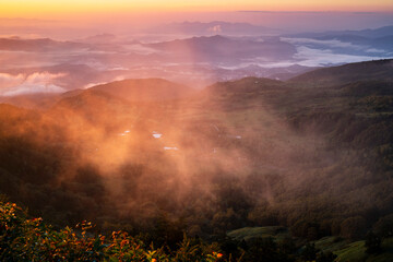 This attached photo shows the view from a mountain peak reached by car early in the morning, with the mountains illuminated by the morning sun (alpenglow).