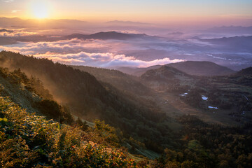 This attached photo shows the view from a mountain peak reached by car early in the morning, with the mountains illuminated by the morning sun (alpenglow).