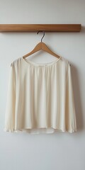 A minimalist scene featuring a sleek blouse on a wooden coathanger