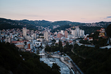 Beautiful sunset view at the blue hour of the small mountain town Uzice in southern Serbia. The river in the gorge. Residential concrete high-rise buildings from the time of Yugoslavia.