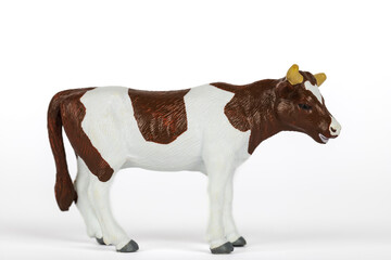 Brown and white plastic toy cow isolated on white background. Concept of farm animals and mammals