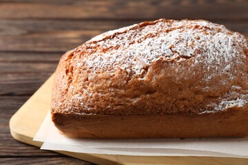 Tasty sponge cake with powdered sugar on wooden table, closeup
