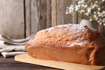 Tasty sponge cake with powdered sugar on wooden table, closeup