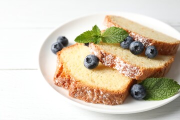 Freshly baked sponge cake, mint and blueberries on white wooden table