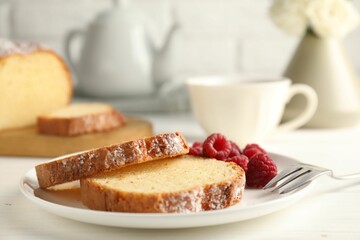 Freshly baked sponge cake and raspberries on white wooden table, closeup