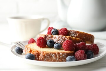 Freshly baked sponge cake, raspberries and blueberries on white wooden table, closeup
