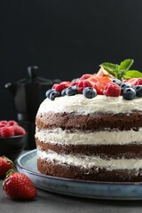 Delicious chocolate sponge cake with berries on grey table, closeup