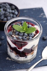 Tasty trifle dessert. Blueberries, sponge cake and whipped cream in glass on light grey table