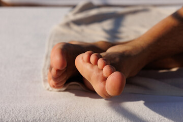 man feet lying on white lounger near sea. Holiday concept. man feet relaxing on sun, enjoying sun, feet 
