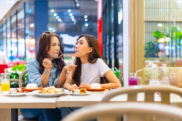 Family relationship, mother's day concept. Happy Asian mother and daughter enjoy outdoor lifestyle shopping and having lunch eating food together in restaurant at shopping mall on holiday vacation.