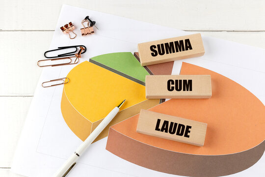 Summa cum laude concept with wooden blocks, pie chart, and office supplies on white background
