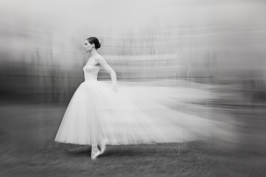 Black and white photo of a ballerina in a full body dress, blurred motion, style of motion blur. High speed photography, long exposure.