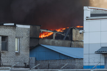 Massive large blaze fire in the city, blazing warehouse factory, storage building is burning,...