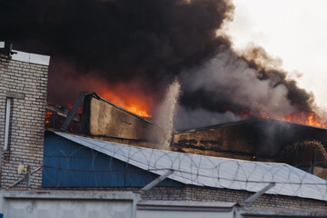 Massive large blaze fire in the city, blazing warehouse factory, storage building is burning,...