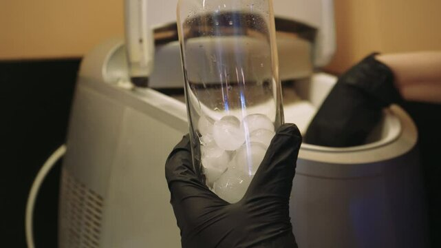 Filling a cocktail glass with ice cubes. The process of adding cocktail ingredients to a glass. Preparation at the bar counter.