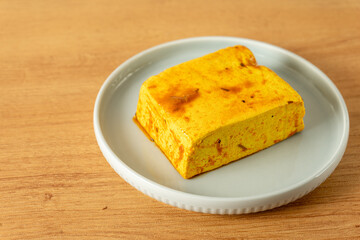 Marinated tofu cube ready for cooking, showcasing a vibrant golden-brown color with herbs and spices. Ideal for healthy meal prep and vegetarian recipes.