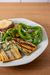 Grilled tofu and vibrant vegetables drizzled with a creamy peanut pesto, beautifully plated to highlight their colors and textures. Perfect for healthy food photography.