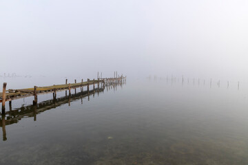 old wooden pier in a fog with reflection