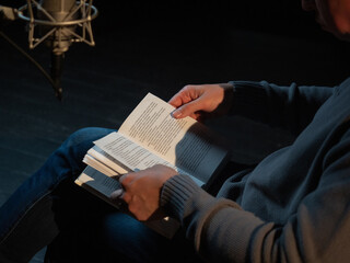 Hand holding a paper book in a dark studio setting.