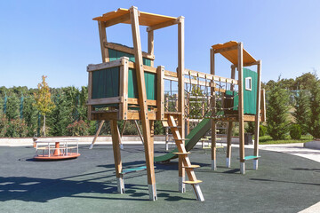 green colored children's wooden playground in the park in the sun