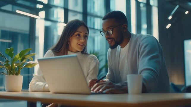two diverse professionals collaborating over laptop, open-plan office, dynamic interaction, contemporary workspace design - Powered by Adobe