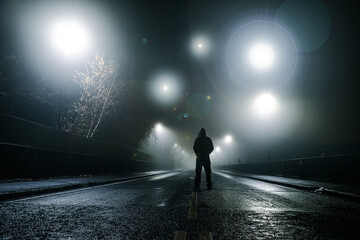 A fantasy, sci fi concept. Of a man standing in the middle of a road with mysterious UFO lights floating above him. On a spooky foggy winters night.
