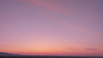 Obraz premium The sky at dawn, with a soft gradient of pink, purple, and orange as the first rays of sunlight peek over the horizon 
