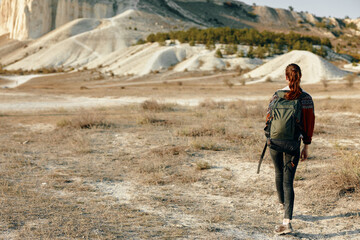 Hiker trekking through desert landscape with majestic mountains in the distance on a sunny day