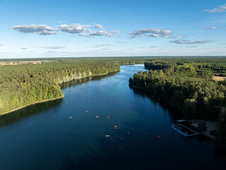 Aerial drone view of people kayaking on a lake surrounded by green forest. Kulka Reserve, Masuria, Poland. Sailing in red kayaks in the Masurian Lake District. Lake Lesk in the Kulka Reserve in Poland