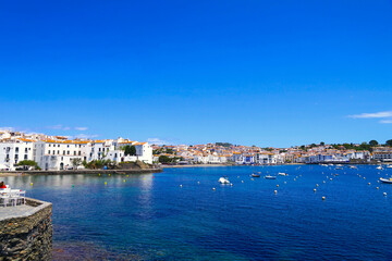 Fototapeta premium view over the Badia de Cadaqués, to the beautiful white houses of Cadaqués, Port Alguer and the turquoise water of the Mediterranean Sea, mountains of the Pyrenees behind, Girona, Catalonia, Spain