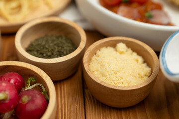 Close up in health food's Ingredients of special menu homemade cooking radish, garlic, salt, oregano, tomato and seasonings placing elements on preparing wooden table on blurred background. Postulate.