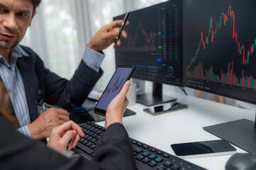 Focusing on phone with discussing dynamic stock market in two business traders online website compare with pc screens in real time currency rate investment on risk data at modern office. Postulate.