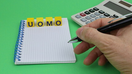 La parola UOMO in italiano scritta su cubi di legno. Qualcuno mette a posto la scritta con una mano...