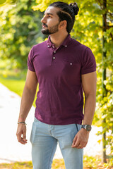 Obraz premium Close-up portrait of a confident, handsome, bearded Asian-Indian man with a ponytail. He's gazing into the distance, showing a range of facial expressions and exuding a calm demeanor.