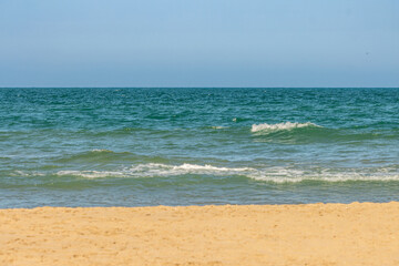 Tranquil Beach Scene with Gentle Waves and Clear Blue Sky Background